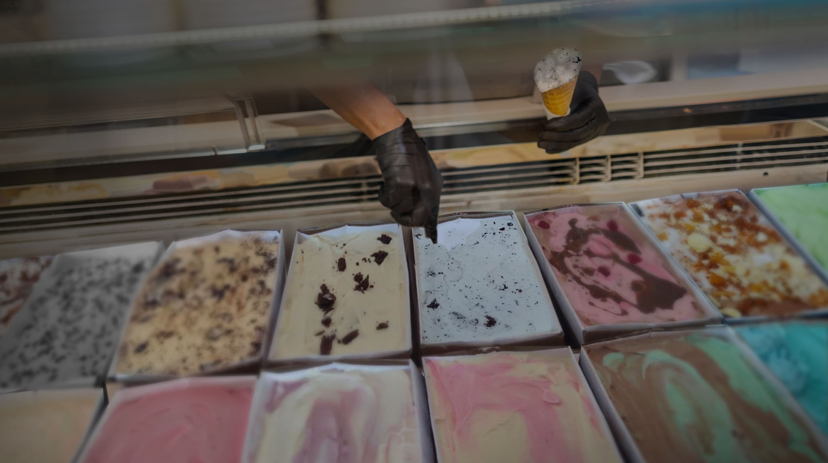 Imagem representando um atendente retirando sorvete em um freezer dentro do Planador Parilla e Bar, no Complexo Esportivo Raboni